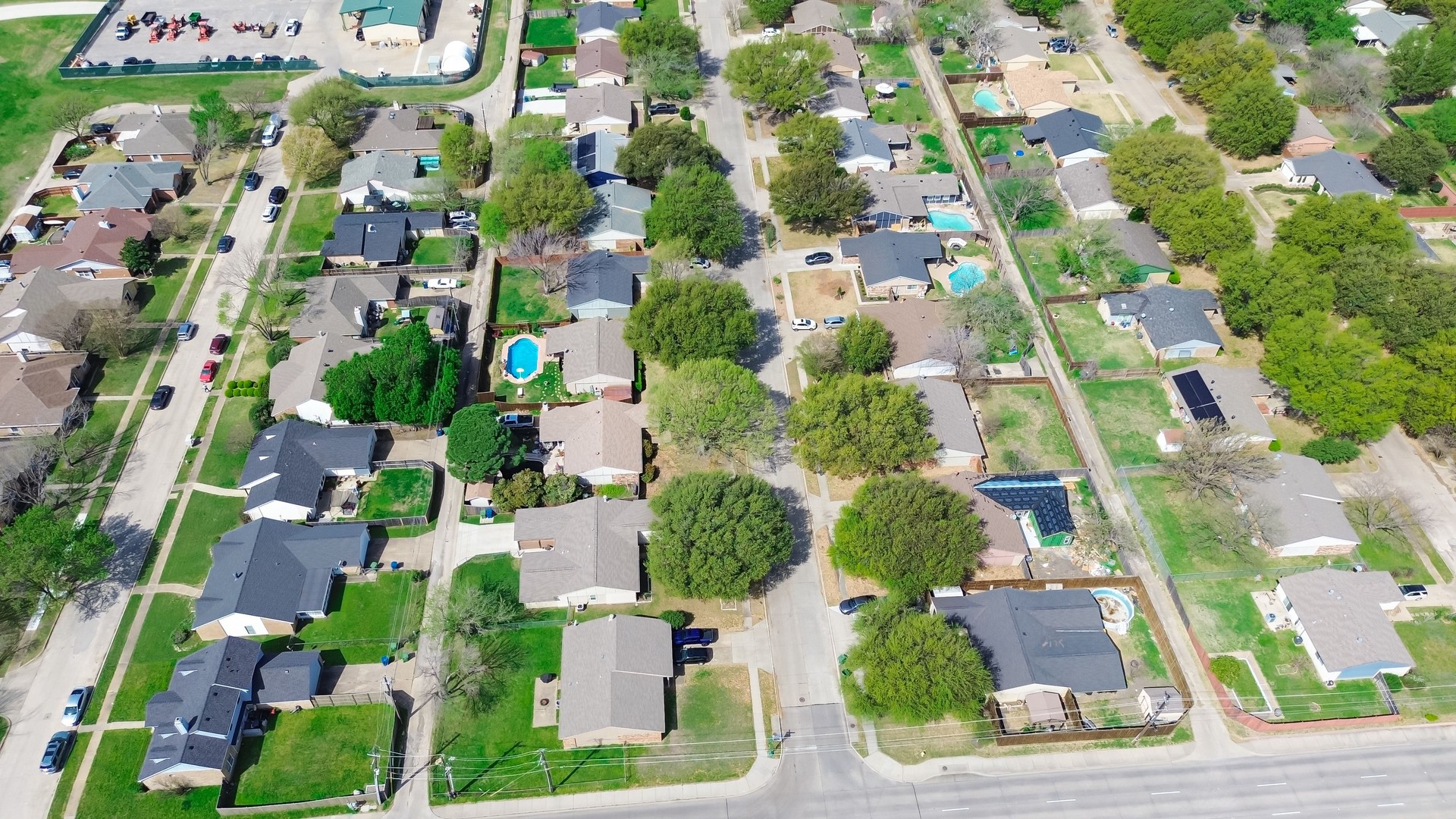 Suburban residential houses near Arbor Glen and Paige Road in The Colony suburb Dallas, Denton County, Texas, detached homes with solar roofing, lush green, swimming pool, large backyard, aerial